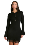 A woman modeling a black ribbed long-sleeve mini dress with a buttoned henley-style neckline and black lace hem, photographed against a plain light gray studio background.