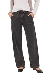 A person wearing dark charcoal gray wide-leg jeans with a drawstring waist, styled with a white long-sleeve top and a light beige cardigan, paired with black flats, against a light beige studio background.