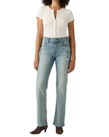 A model wearing light-wash blue straight-leg jeans, a cream ribbed short-sleeve top, and brown heeled boots, standing against a light gray studio background.
