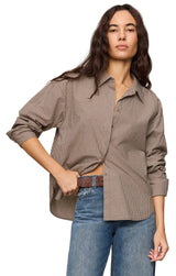 Woman wearing a brown checkered shirt and blue jeans on a beige background